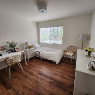 A minimalist bedroom with a neatly arranged bed, desk, chairs, and decor.