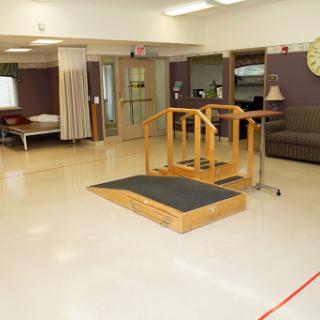 A rehabilitation therapy room featuring a wooden ramp with handrails, designed for patient mobility and accessibility.