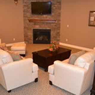 A cozy living room with a stone fireplace and comfortable seating.
