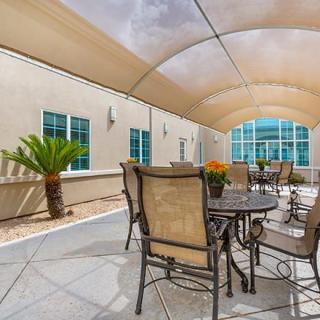 A shaded outdoor patio area with tables and chairs.