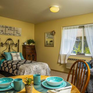 A cozy bedroom with yellow walls, featuring a single bed and a small dining area.