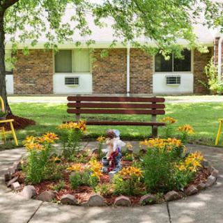 A serene garden space featuring vibrant flowers, a wooden bench, and a peaceful atmosphere.