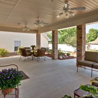 A spacious covered patio with outdoor furniture, surrounded by a well-maintained garden.
