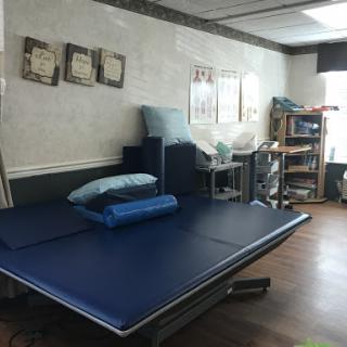 A therapy room equipped with blue mats and various rehabilitation tools, designed for a calming and supportive atmosphere.
