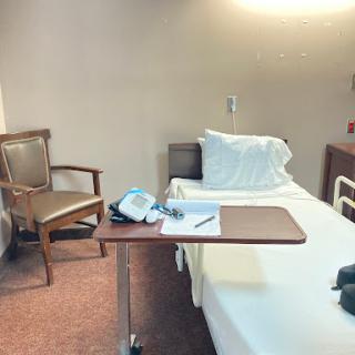 A serene hospital patient room with a bed, chair, and medical equipment.