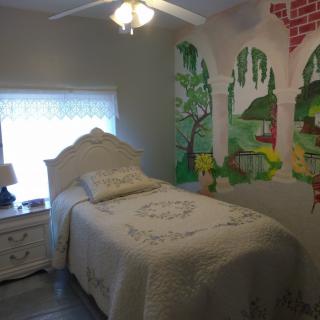A cozy bedroom with a single bed and colorful wall mural.