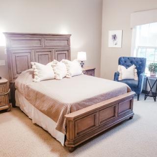 A cozy and elegantly furnished bedroom featuring a comfortable bed, stylish nightstands, and a blue accent chair.