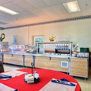 A well-organized cafeteria buffet setup with a variety of food options and a cozy dining area.