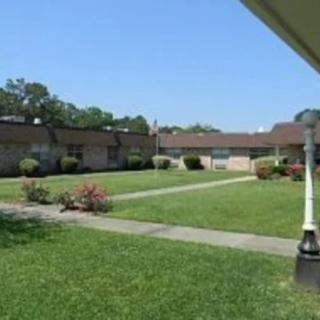 A view of a grassy courtyard surrounded by low buildings under a clear blue sky.