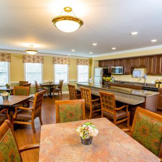 A cozy dining area with a kitchen, featuring multiple tables and chairs.