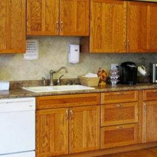 A kitchen with wooden cabinets, a sink, countertop, and appliances including a dishwasher and coffee maker.