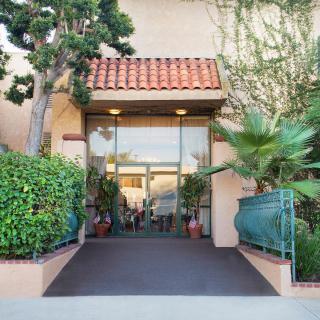 A building entrance with glass doors and surrounding greenery.
