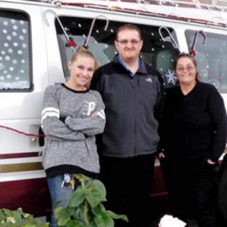 Three people stand in front of a decorated van.