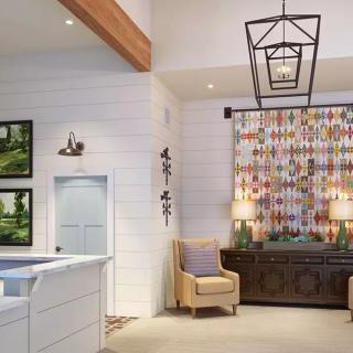 A modern living room with a chandelier, colorful artwork, and a comfortable armchair.