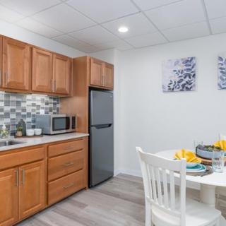 A modern kitchen and dining area featuring wooden cabinets, a compact refrigerator, and a neatly set table.