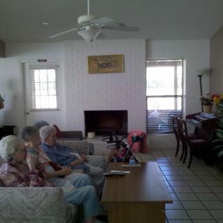 People sitting on a couch in a living room with a fireplace and television.