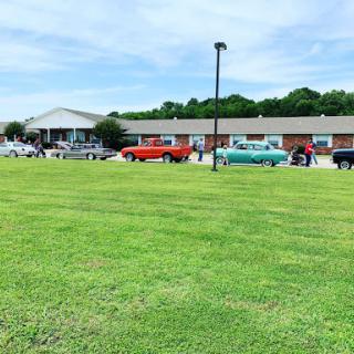 A lineup of vintage cars parked in front of a building on a sunny day.