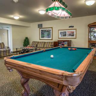 A cozy game room featuring a classic pool table under warm lighting.