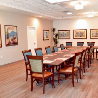 A spacious conference room featuring a long wooden table surrounded by chairs and decorated with framed artwork.
