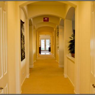 A warmly lit hallway with doors along the sides and artwork on the walls.