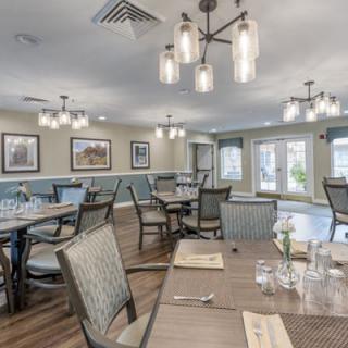 An elegant dining room with neatly set tables and stylish chandeliers.