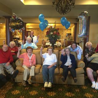 A group of seniors celebrating with balloons in a cozy living room setting.