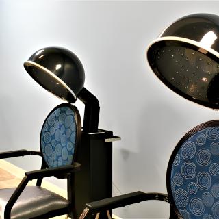 Empty hair salon chairs with hooded hair dryers.