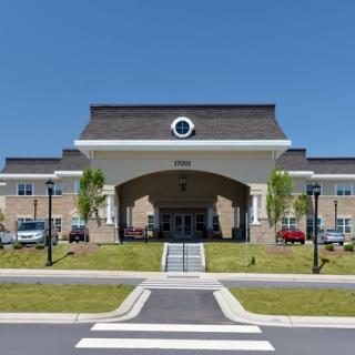 A modern hospital building with an arched entrance and clear blue sky.