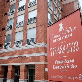 Exterior view of a senior living community building with a sign advertising affordable housing and services.