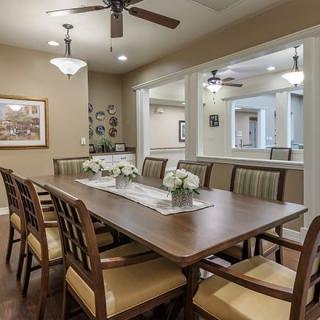 A well-furnished dining room with a large wooden table and chairs, plemented by ceiling fans and decorative elements.