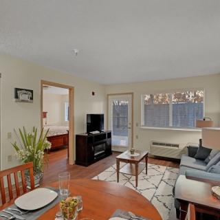 A cozy living room with a sofa, TV, dining table, and large window.