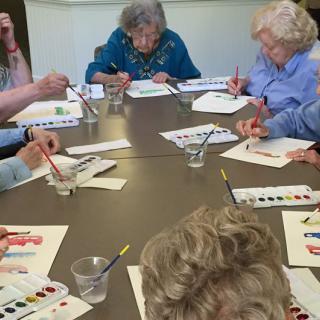 A group of elderly individuals engaged in a watercolor painting activity.