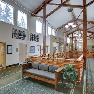 A spacious and well-lit lobby area featuring wooden beams, comfortable seating, and large windows.