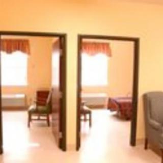 A view of two rooms with open doors and furniture inside, including chairs and a window.