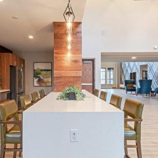 A modern kitchen and dining area featuring a central island with bar stools, wood accents, and pendant lighting in an open space.