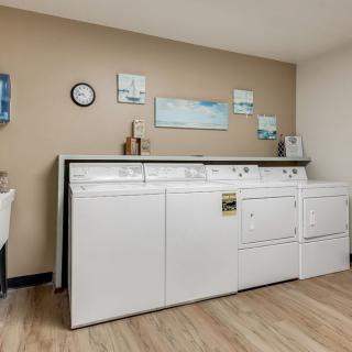 A laundry room equipped with white washing machines and a dryer, featuring neat decor on the walls.