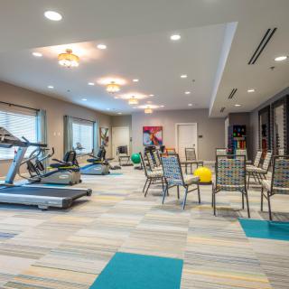 A modern gym equipped with treadmills, exercise machines, and seating in a well-lit indoor space.