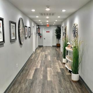 A modern hallway adorned with artwork and greenery, featuring warm lighting and wooden flooring.