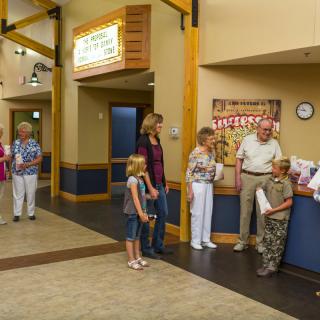 People waiting in a lobby area near a reception desk.