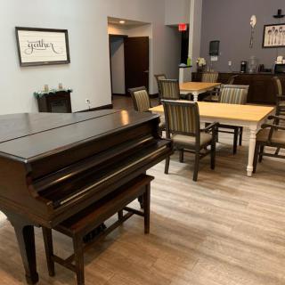 A cozy lounge area featuring a piano and dining tables with chairs.