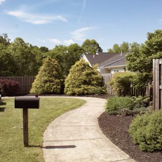 A beautifully landscaped garden with a winding pathway, surrounded by lush greenery and trees.