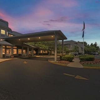 A hospital entrance at dusk with exterior lighting and a parking area.