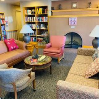 A cozy living room with comfortable sofas, bookshelves, and a fireplace.