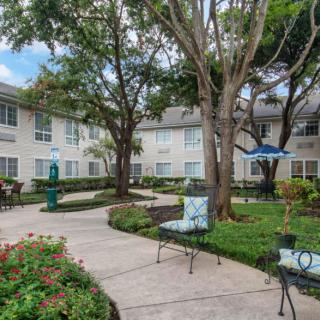 A well-maintained courtyard with benches and lush greenery in an apartment complex.