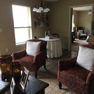 A cozy living room with two armchairs and a round table by the window.