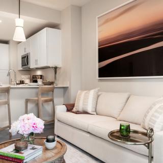 A modern living space with a cozy couch and kitchen area, featuring contemporary artwork and stylish decor.