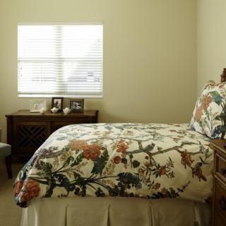 A cozy bedroom with floral bedding and a window letting in natural light.