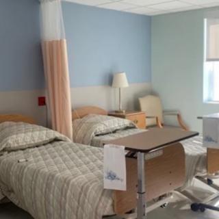 A clean and organized hospital room with two beds and medical equipment.