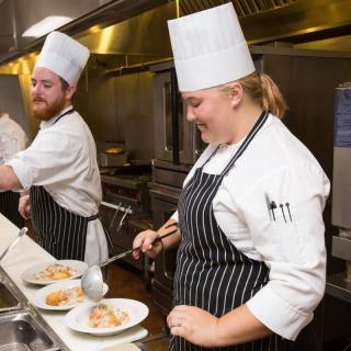 Chefs preparing dishes in a professional kitchen.