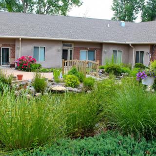 A beautiful garden in front of a house with various plants and flowers.